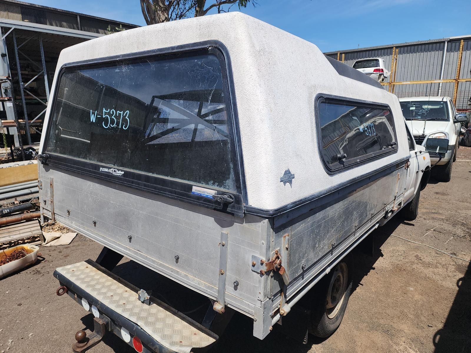 White Utility Truck Canopy on a Flatbed Trailer in a Yard — South West 4WD Wreckers In Harristown, QLD