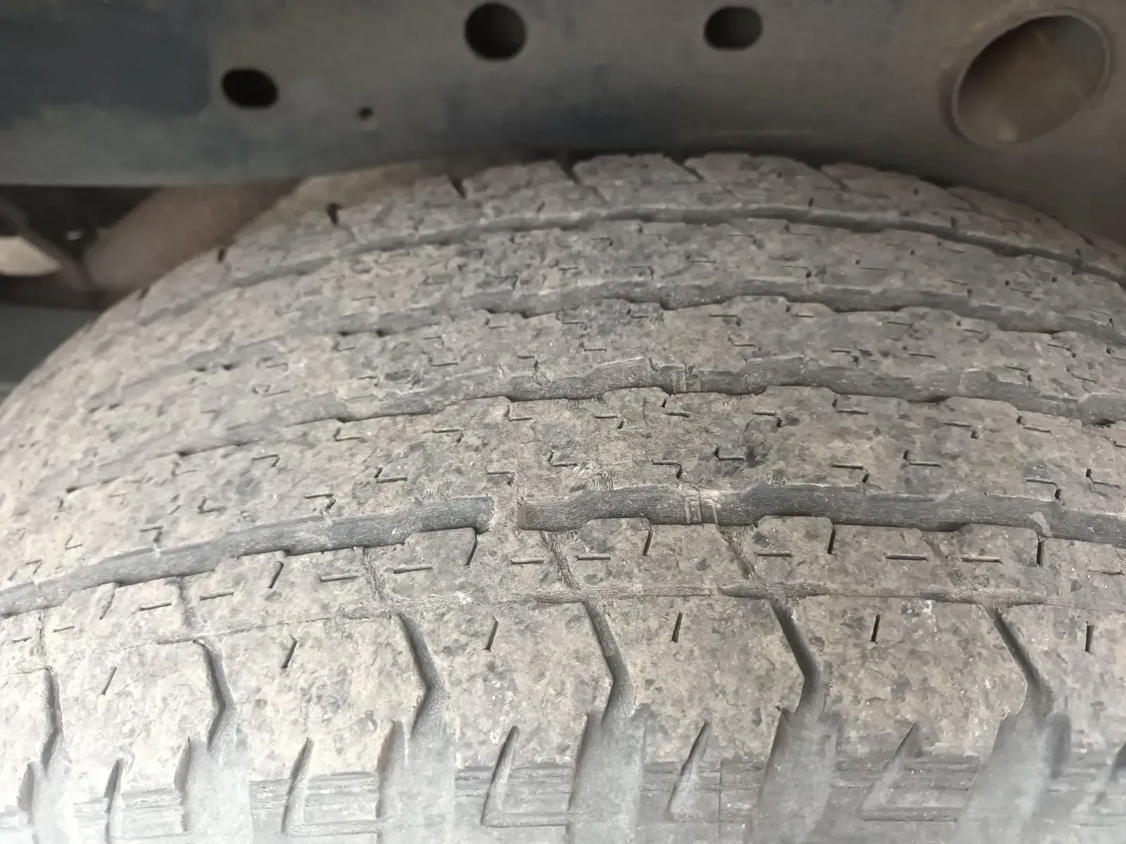 Close-up of a Worn Tyre Mounted Under a Vehicle, Showing Tread Pattern and Dirt — South West 4WD Wreckers In Harristown, QLD