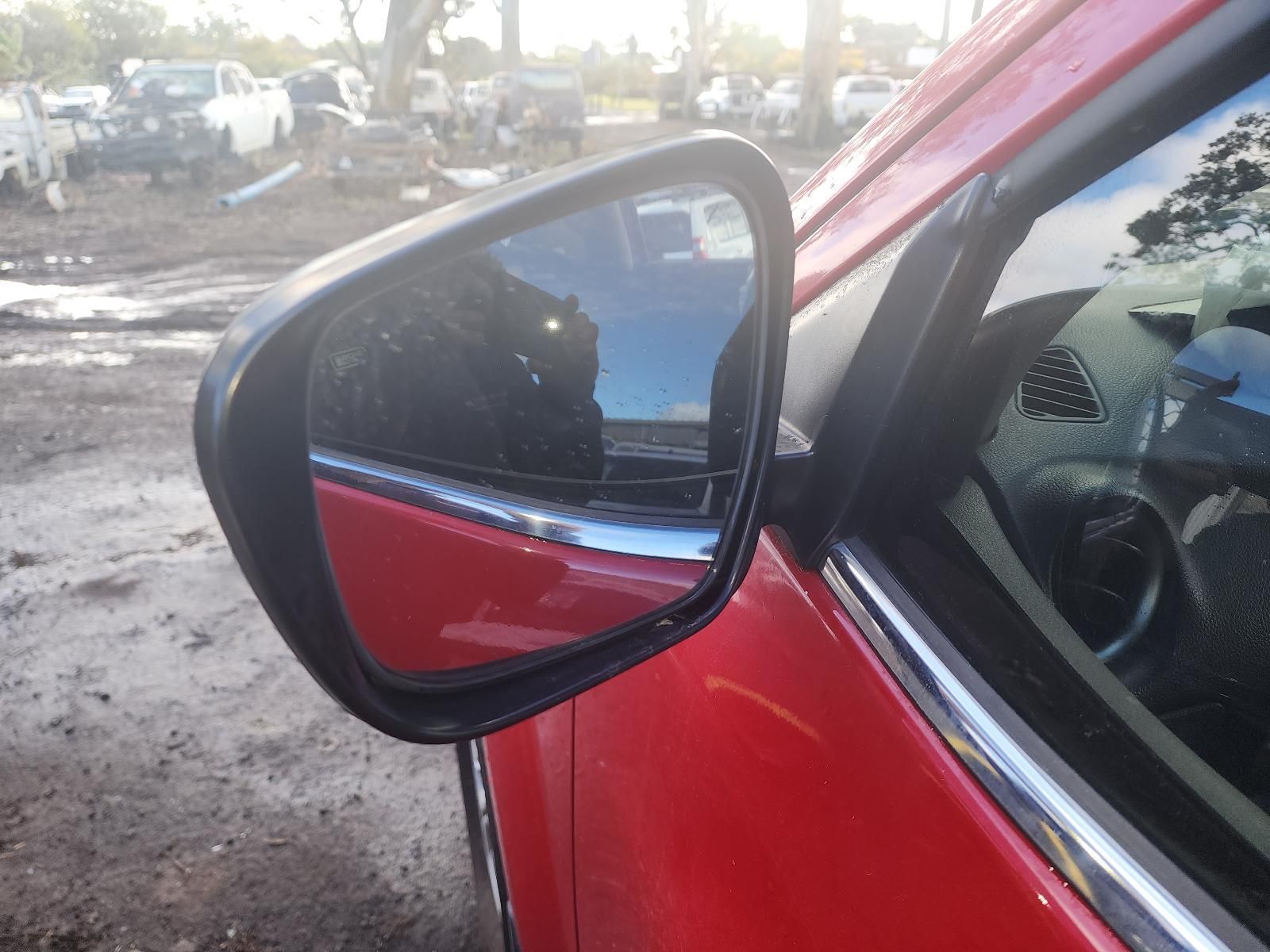 Red Car Side Mirror Reflecting a Muddy Outdoor Lot — South West 4WD Wreckers In Harristown, QLD