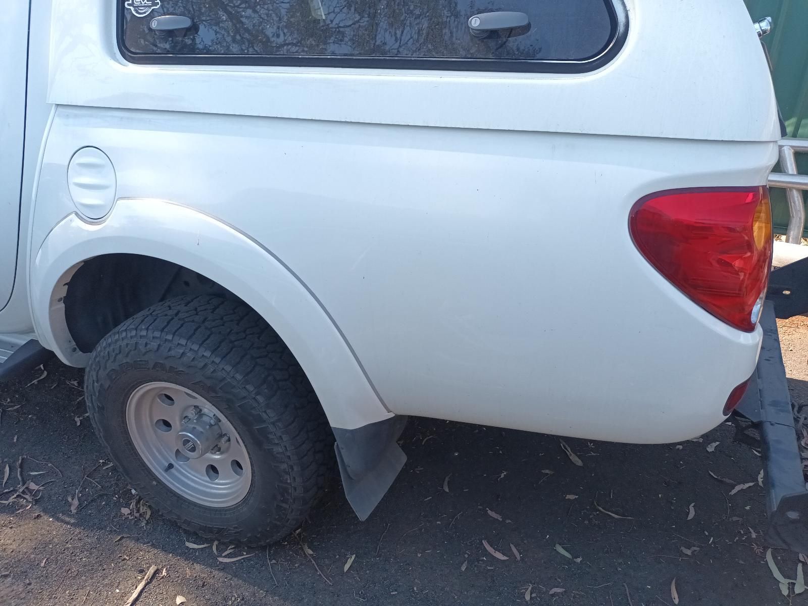 White Pickup Truck Parked on Dirt, Rear Wheel Visibly Damaged and Tilted Inward — South West 4WD Wreckers In Harristown, QLD