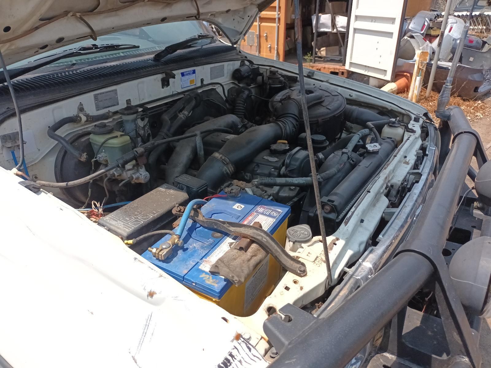 Open Car Engine Bay with Blue Battery and Exposed Hoses Under the Hood — South West 4WD Wreckers In Harristown, QLD