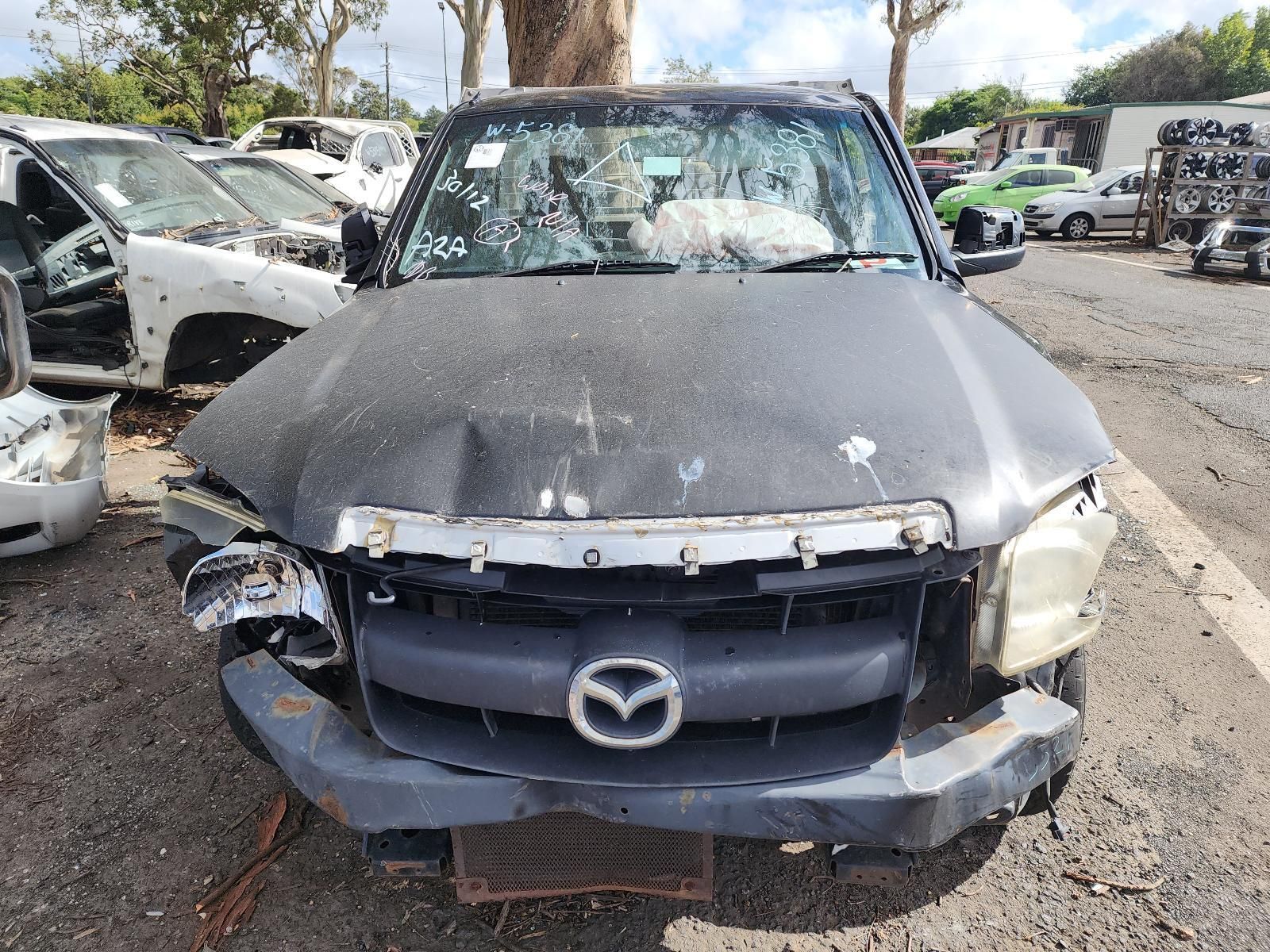 Front View of a Heavily Damaged Black Mazda in a Junkyard — South West 4WD Wreckers In Harristown, QLD