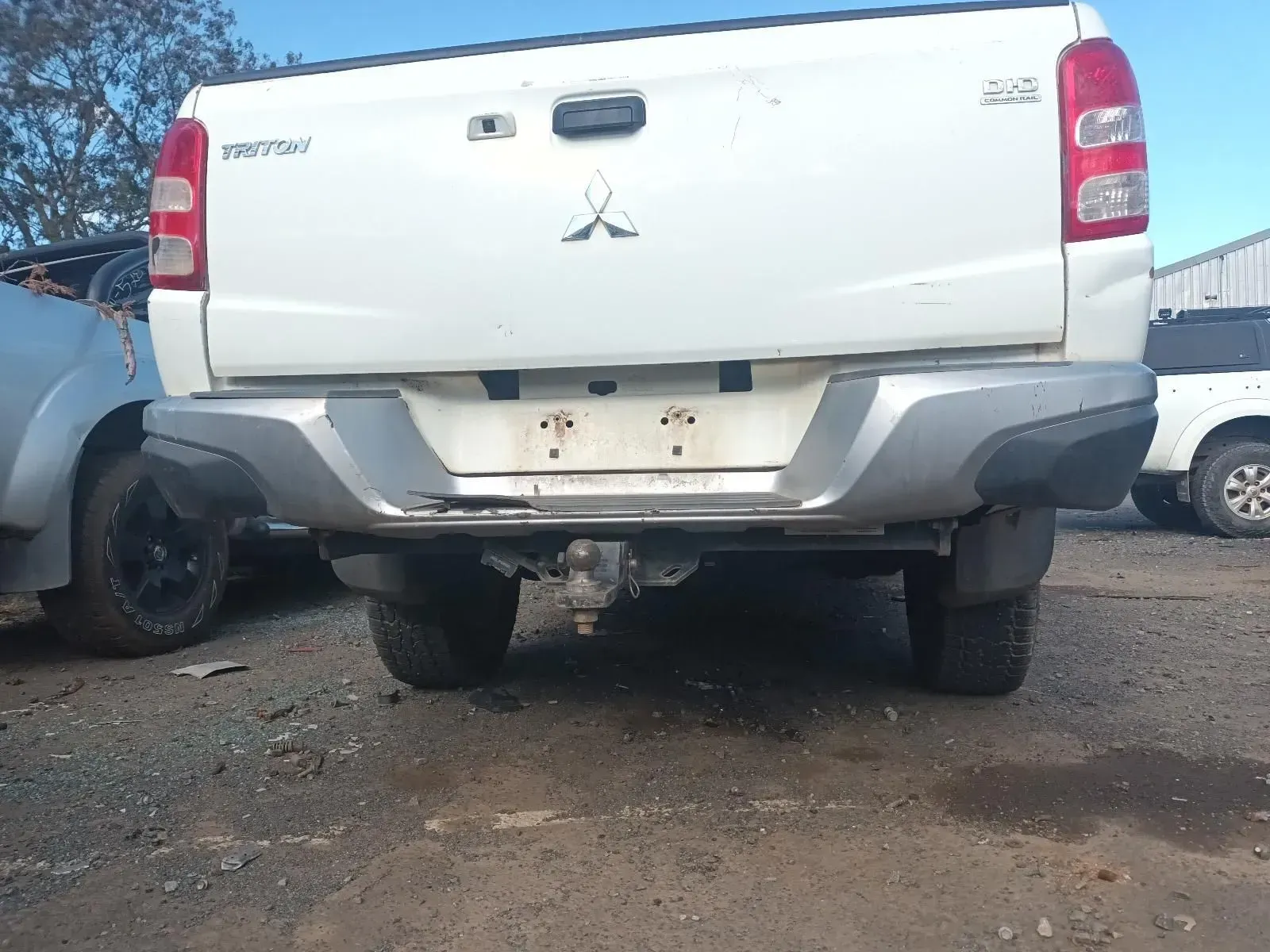 Rear View of a White Mitsubishi Triton Truck With a Tow Hitch in a Salvage Yard — South West 4WD Wreckers In Harristown, QLD