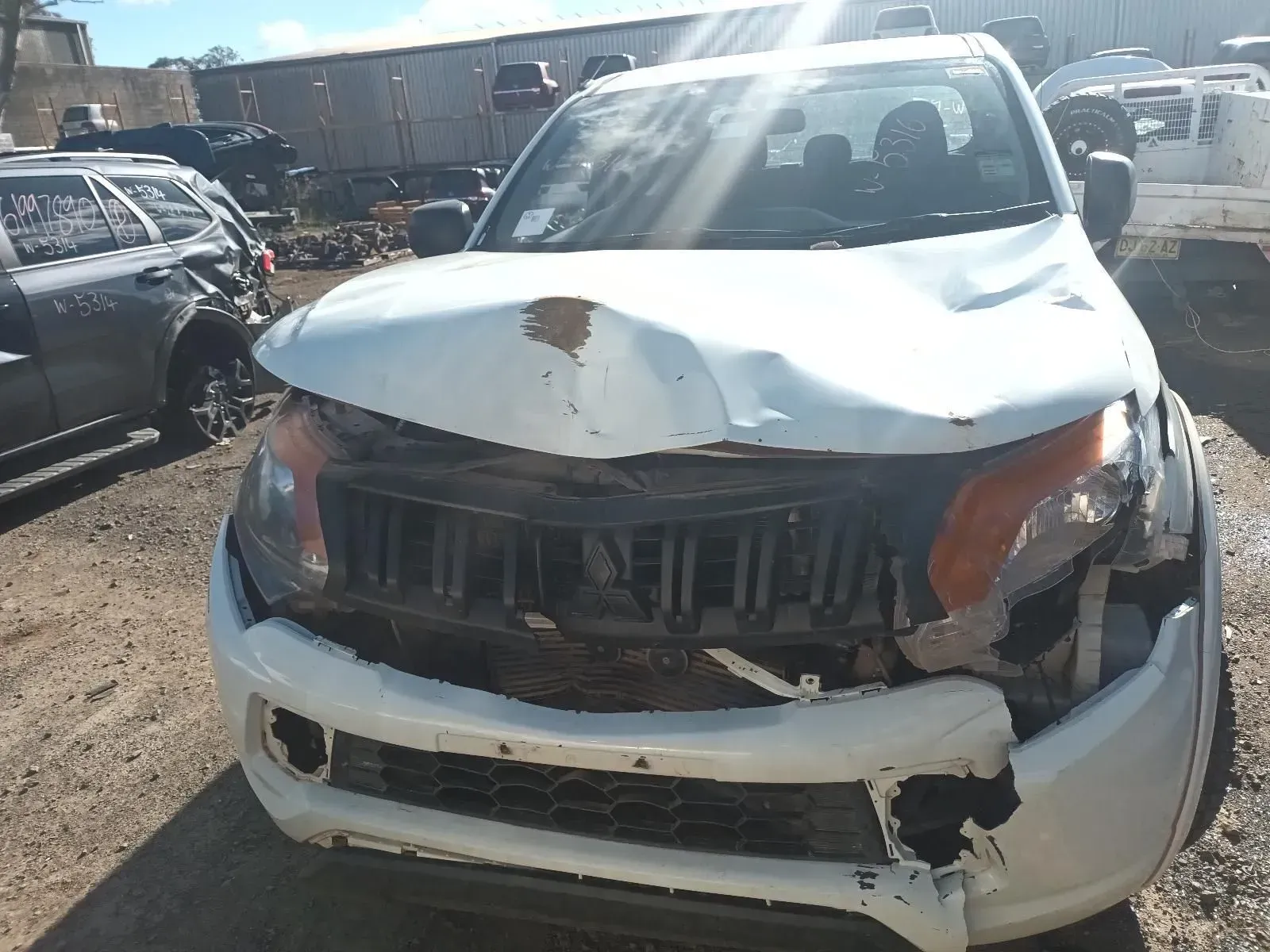 Damaged White Truck With Crumpled Hood and Broken Grill in a Salvage Yard — South West 4WD Wreckers In Harristown, QLD