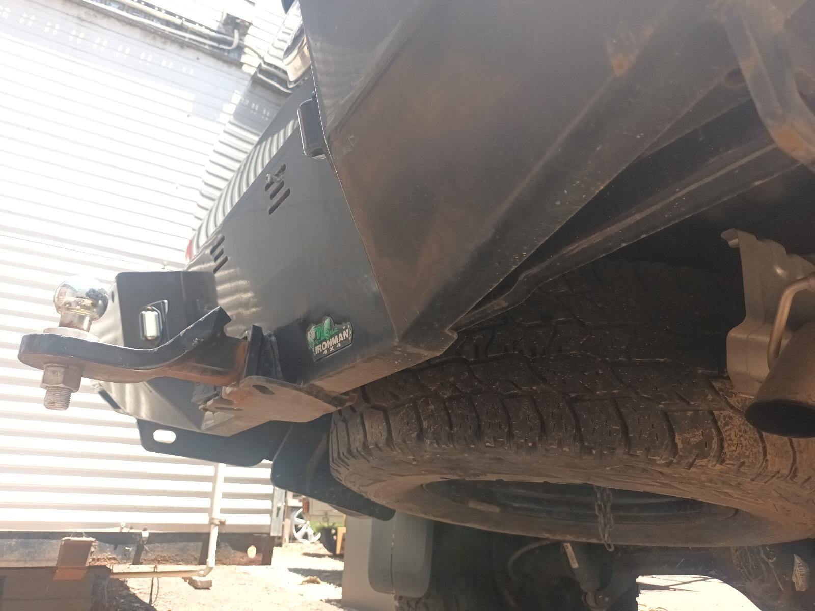 Close-Up of A Truck’s Front Wheel and Bumper with Visible Damage Near a Building — South West 4WD Wreckers In Harristown, QLD
