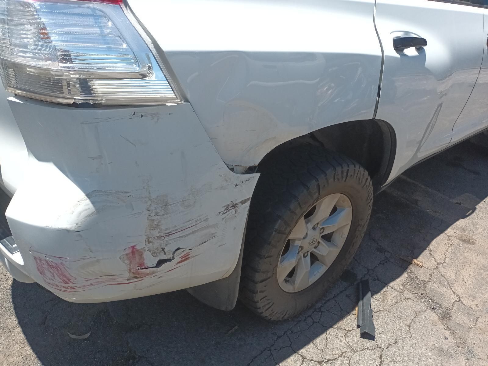 White Suv with Rear-Left Bumper Damage and A Flat Tire on A Cracked Road Surface — South West 4WD Wreckers In Harristown, QLD