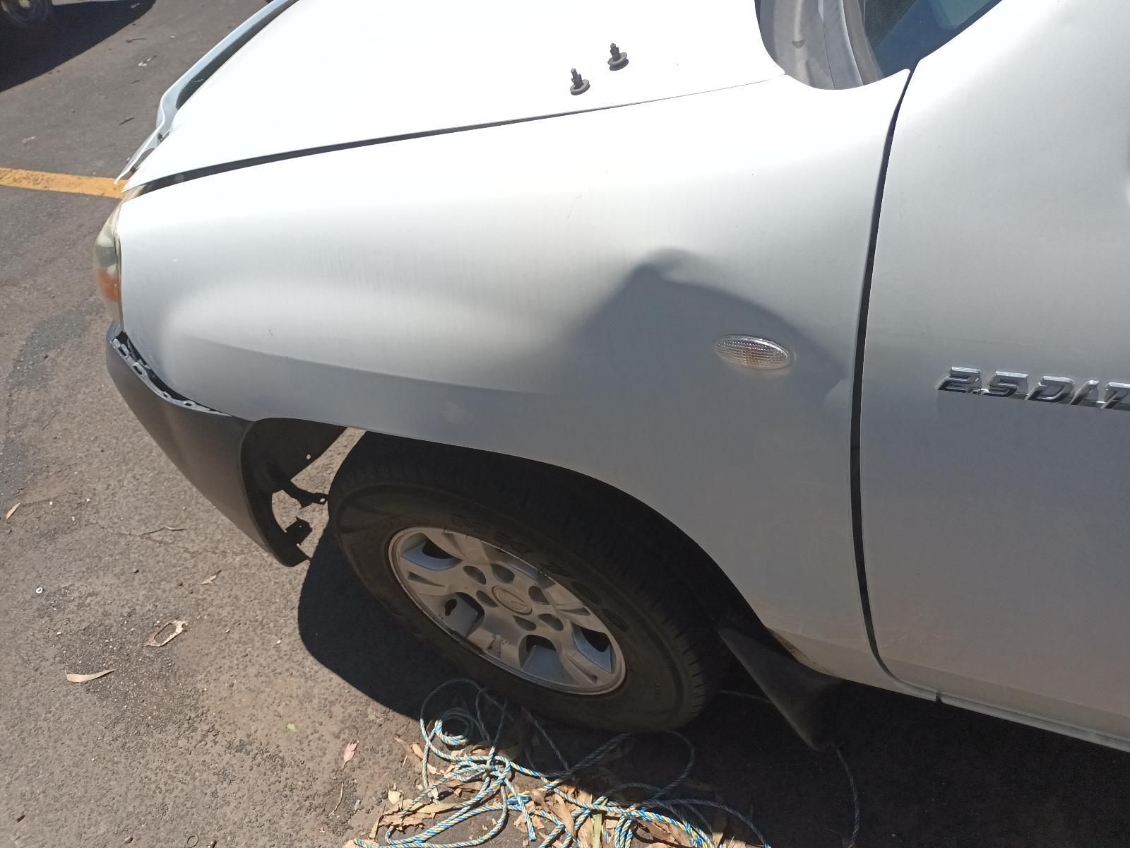 Silver Pickup Truck with A Damaged Front Fender and Flat Tire on A Street — South West 4WD Wreckers In Harristown, QLD