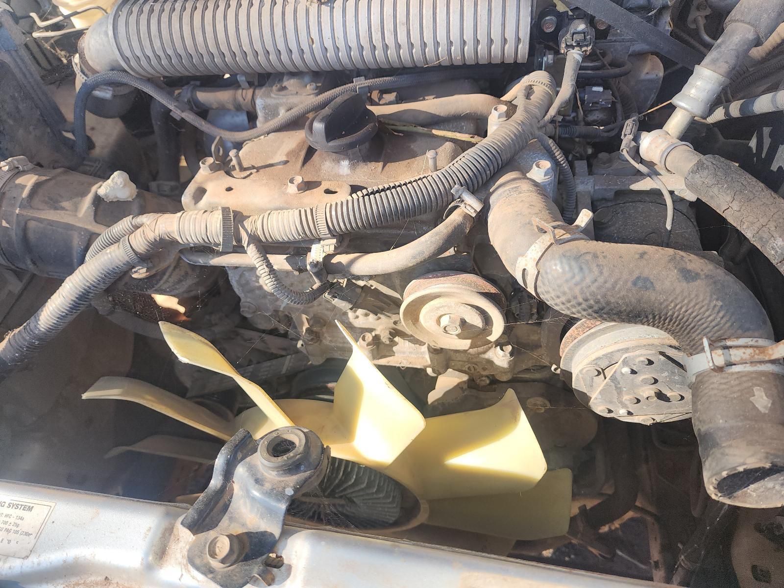 Car Engine Bay with Dusty Hoses, Belts, and A Yellow Fan Blade Visible — South West 4WD Wreckers In Harristown, QLD