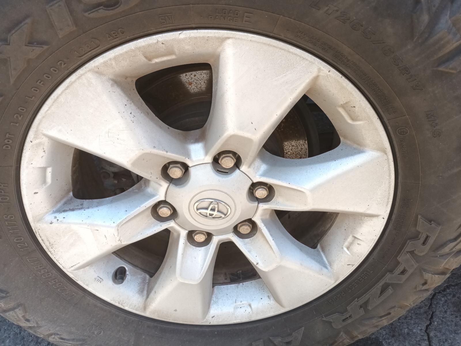 Close-Up of A Dirty Silver Five-Spoke Car Wheel with A Tire and Center Hub Logo — South West 4WD Wreckers In Harristown, QLD