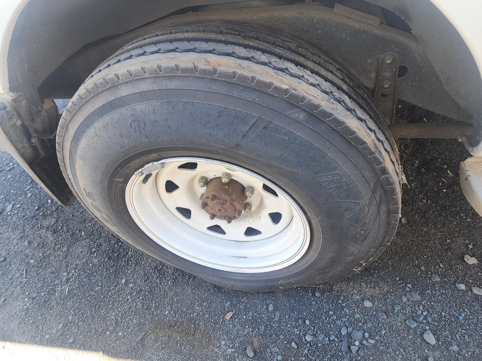 Close-Up of A Worn Vehicle Tyre with A White Steel Rim on A Gravel Surface — South West 4WD Wreckers In Harristown, QLD
