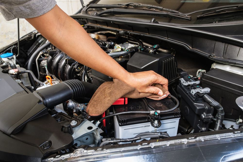 A Person Wiping the Battery Terminal Inside a Car's Engine — O'Toole Automotive In Tuggerah, NSW