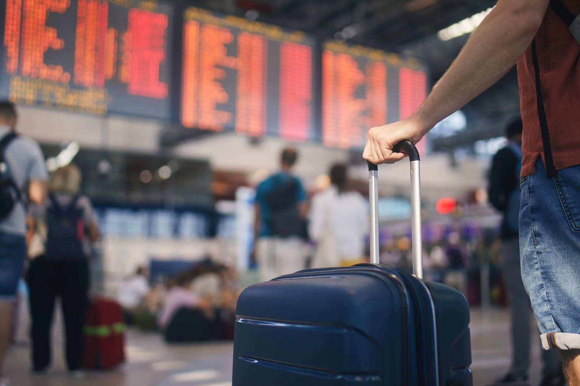 A man is holding a suitcase in an airport.