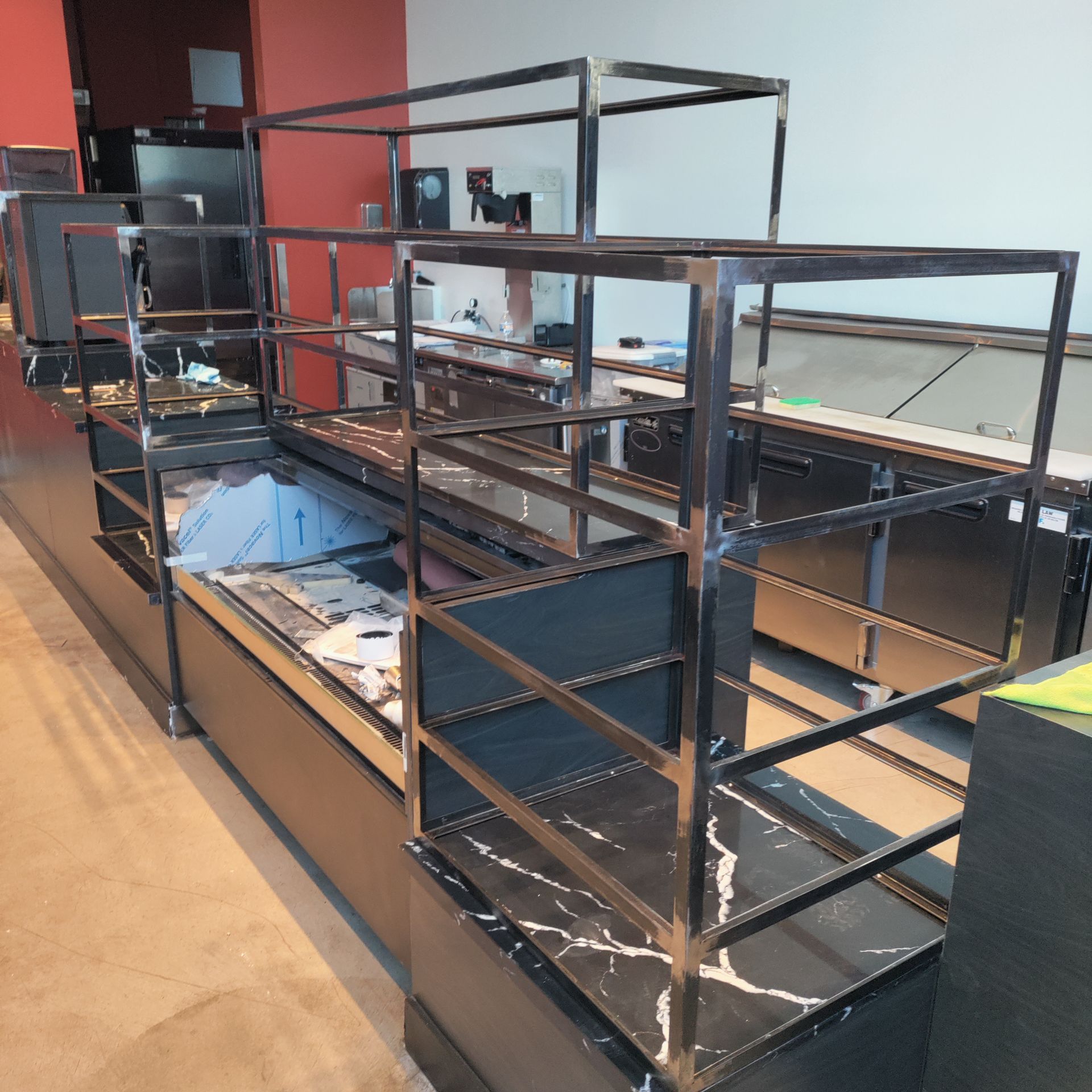 Empty black display shelving in a store. Steel frame with three tiers on marble countertop.