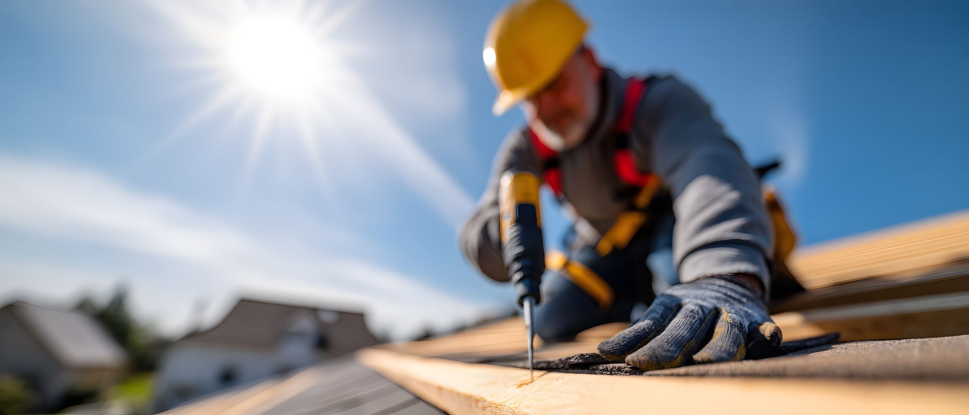 A focused roofer meticulously fastens roofing material under a bright, sunny sky. A focused roofer meticulously fastens roofing material under a bright, sunny sky.