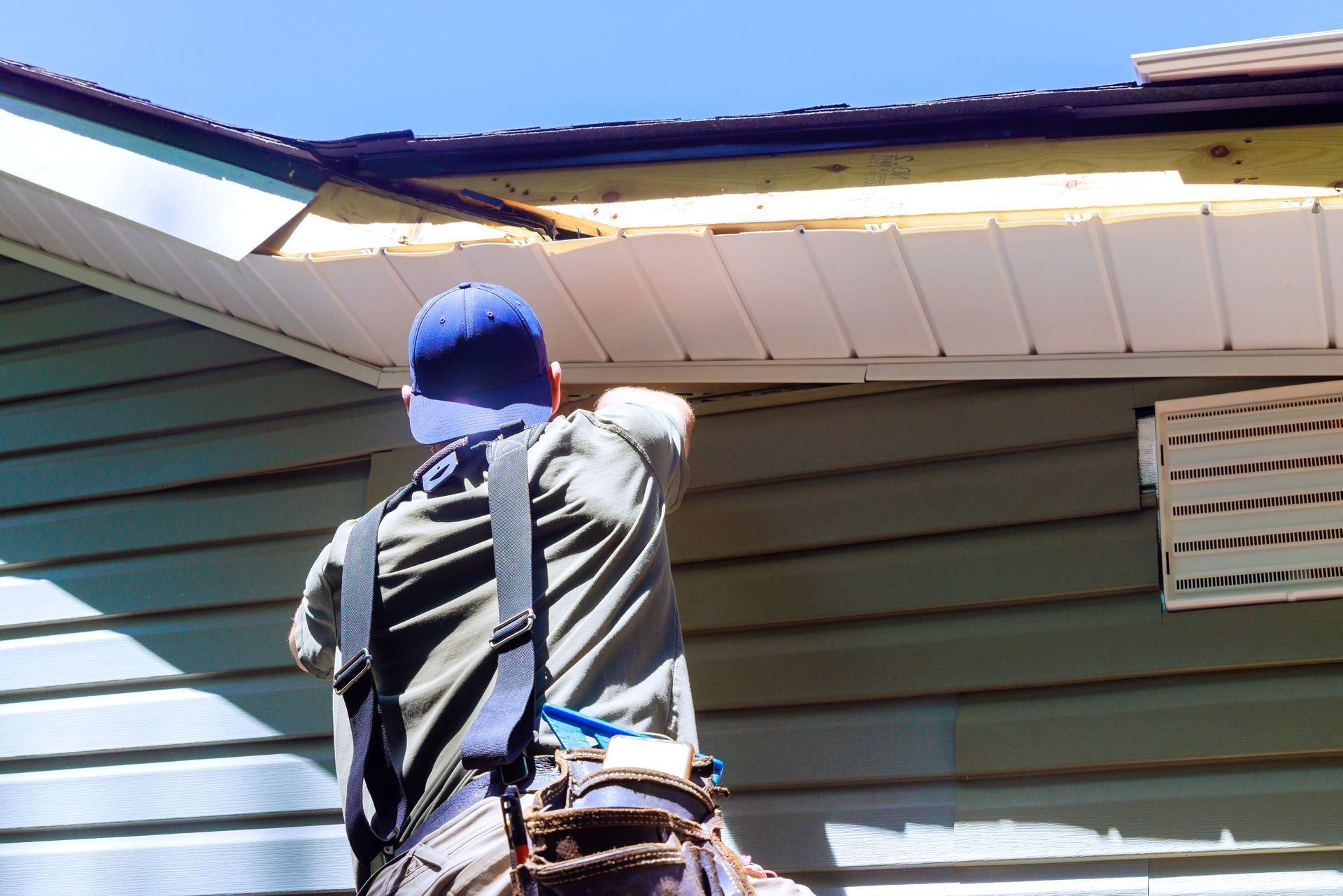 Contractor installing siding and soffit on a house exterior Contractor installing siding and soffit on a house exterior