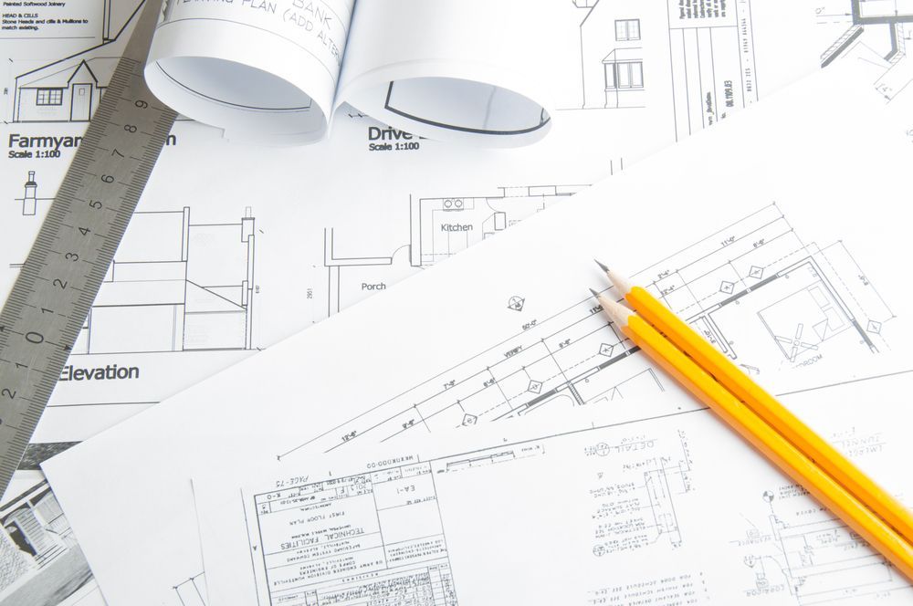 Architectural Blueprints With Rolled Plans, Pencils, And Ruler On A White Surface — GS Design & Drafting In Rous, NSW