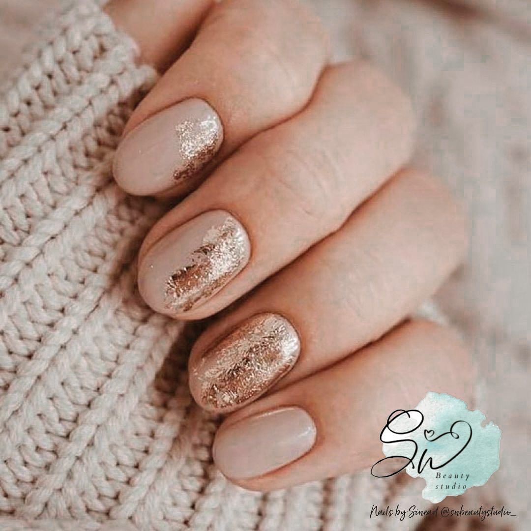 Close-up of nude and rose-gold glitter manicure on short, rounded nails.