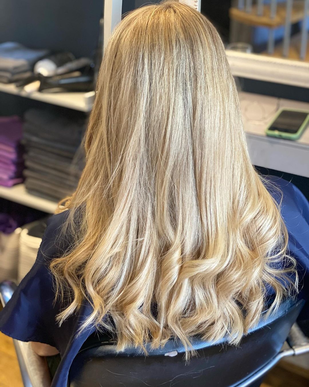Person with long blonde hair seated in an office chair, seen from behind.