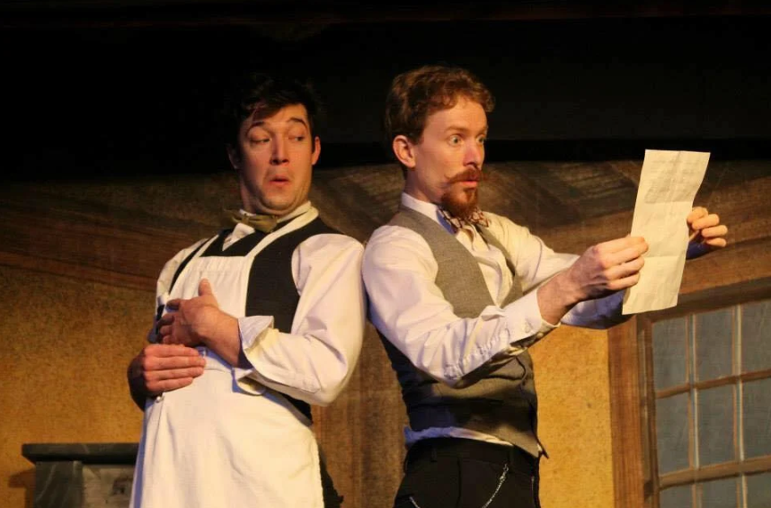 Two men are standing next to each other looking at a piece of paper.