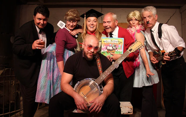 A group of people posing for a picture including a man holding a banjo