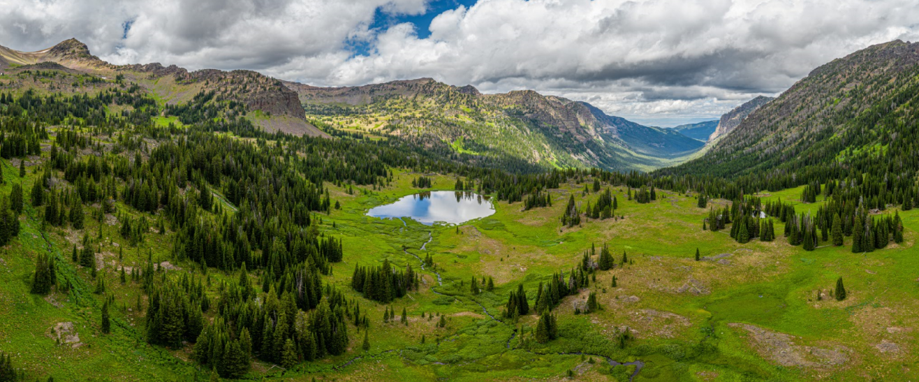 An aerial view of a mountain valley with a small lake in the middle.