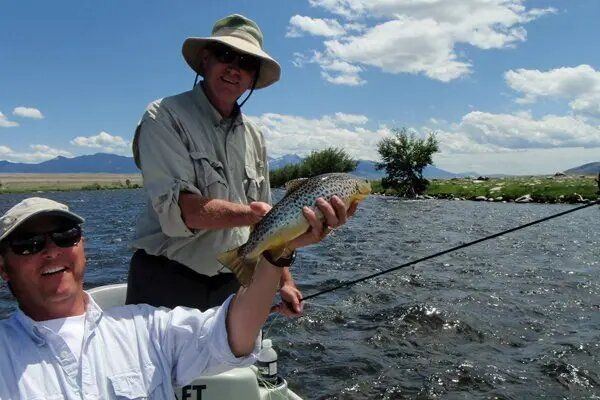 Two men are fishing in a river and one of them is holding a fish