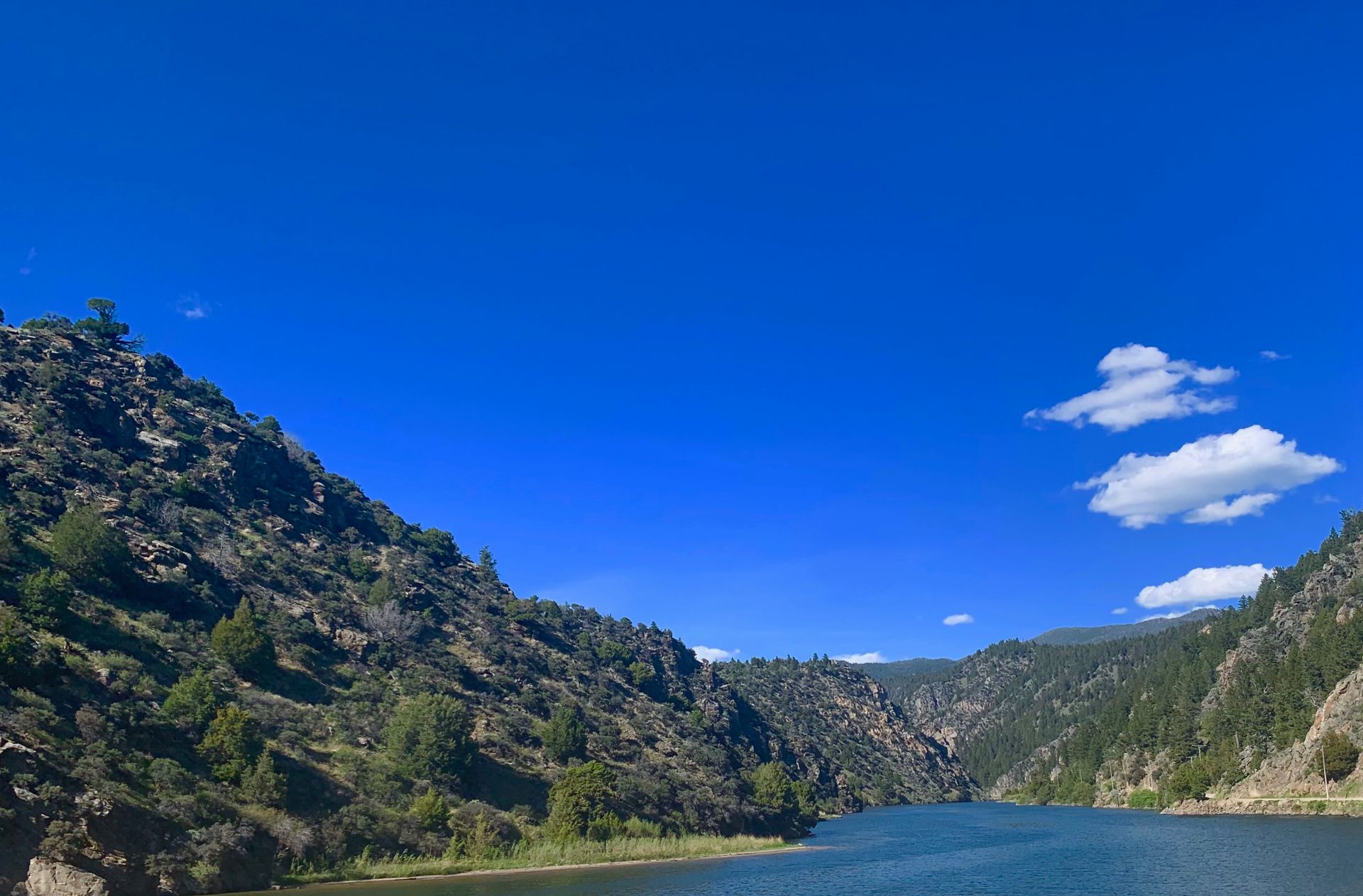 A lake surrounded by mountains and trees on a sunny day