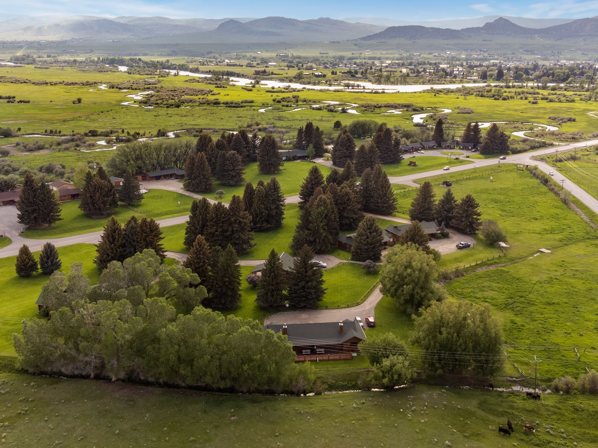 An aerial view of a house in the middle of a lush green field surrounded by trees.