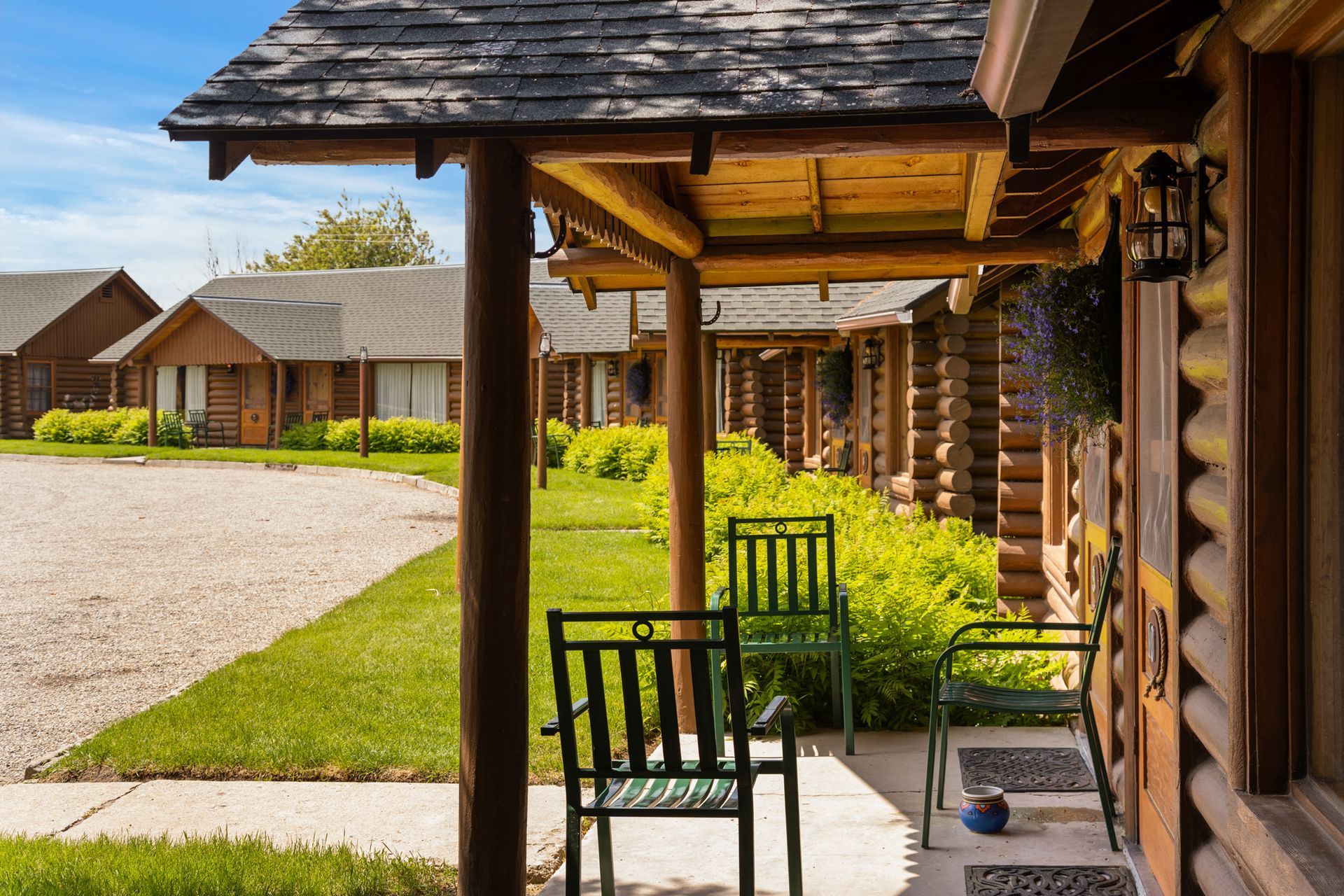 A porch with two chairs and a table in front of a log cabin.