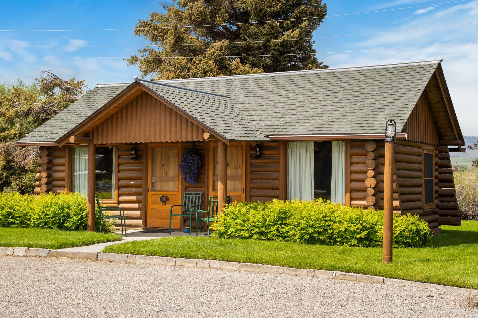 A small log cabin is sitting in the middle of a lush green field.