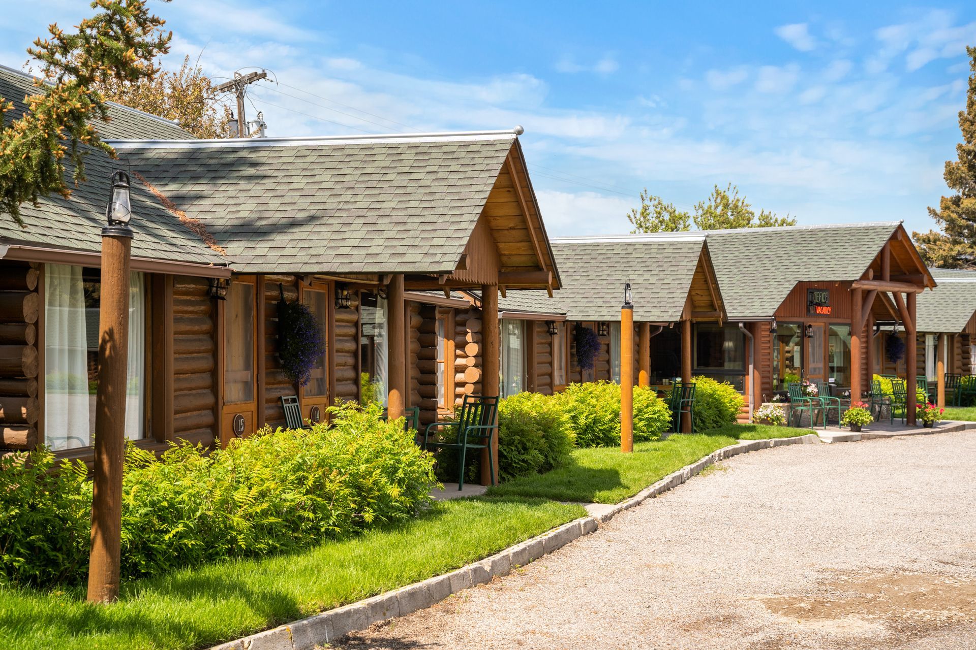 A row of small wooden cabins with a gravel driveway leading to them.