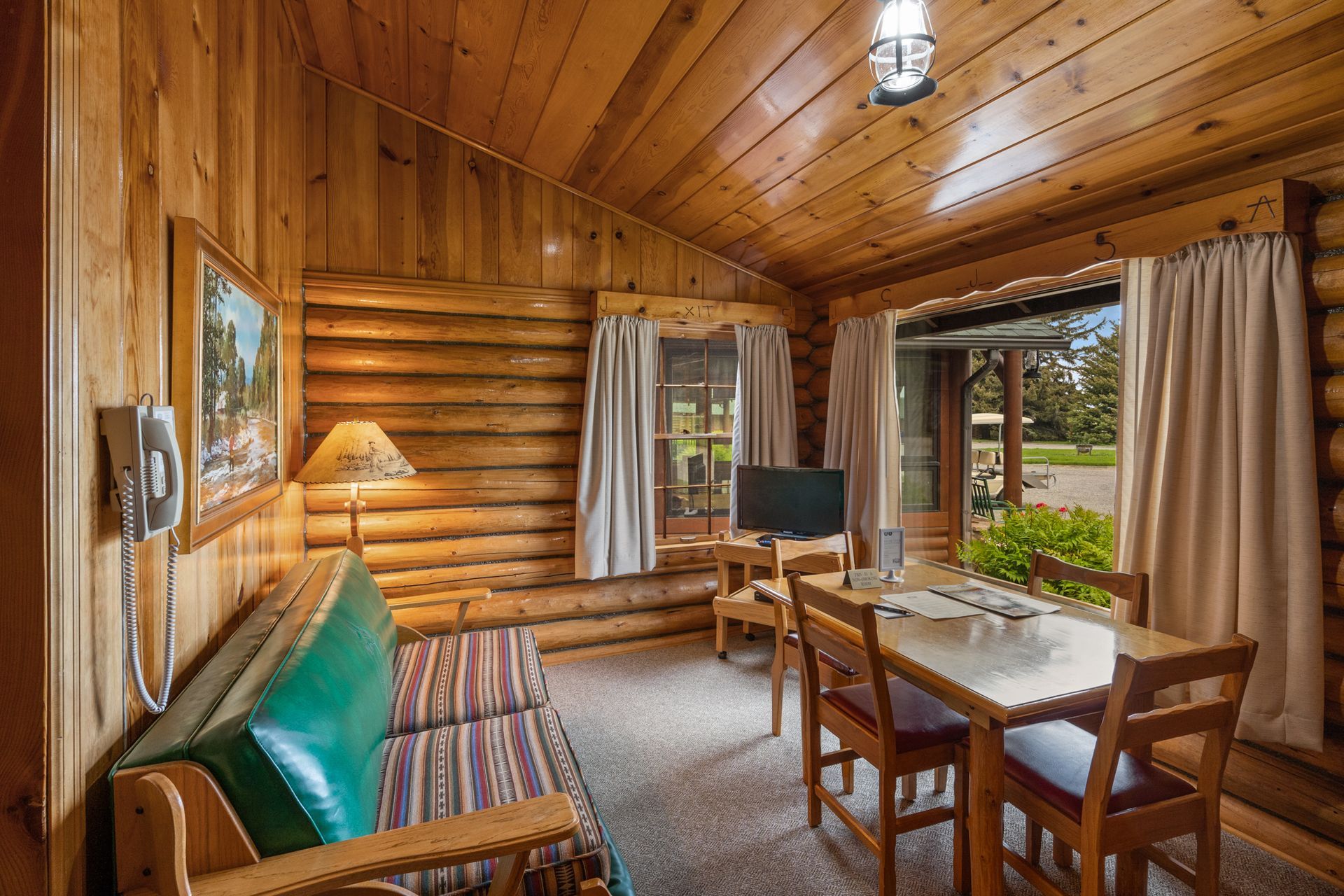 A living room in a log cabin with a couch , table and chairs.
