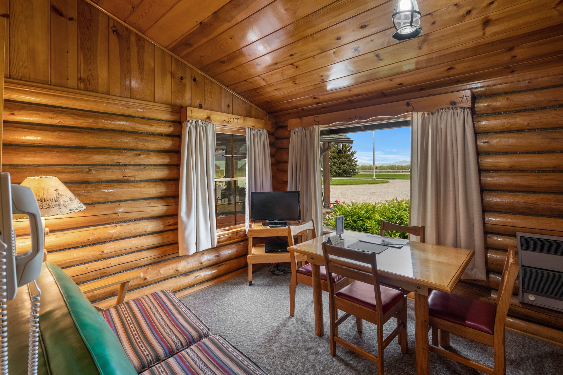 A living room in a log cabin with a table and chairs.