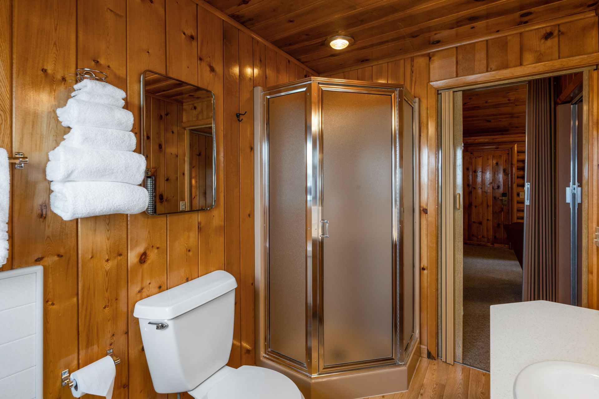 A bathroom with a toilet , sink , mirror and shower stall.