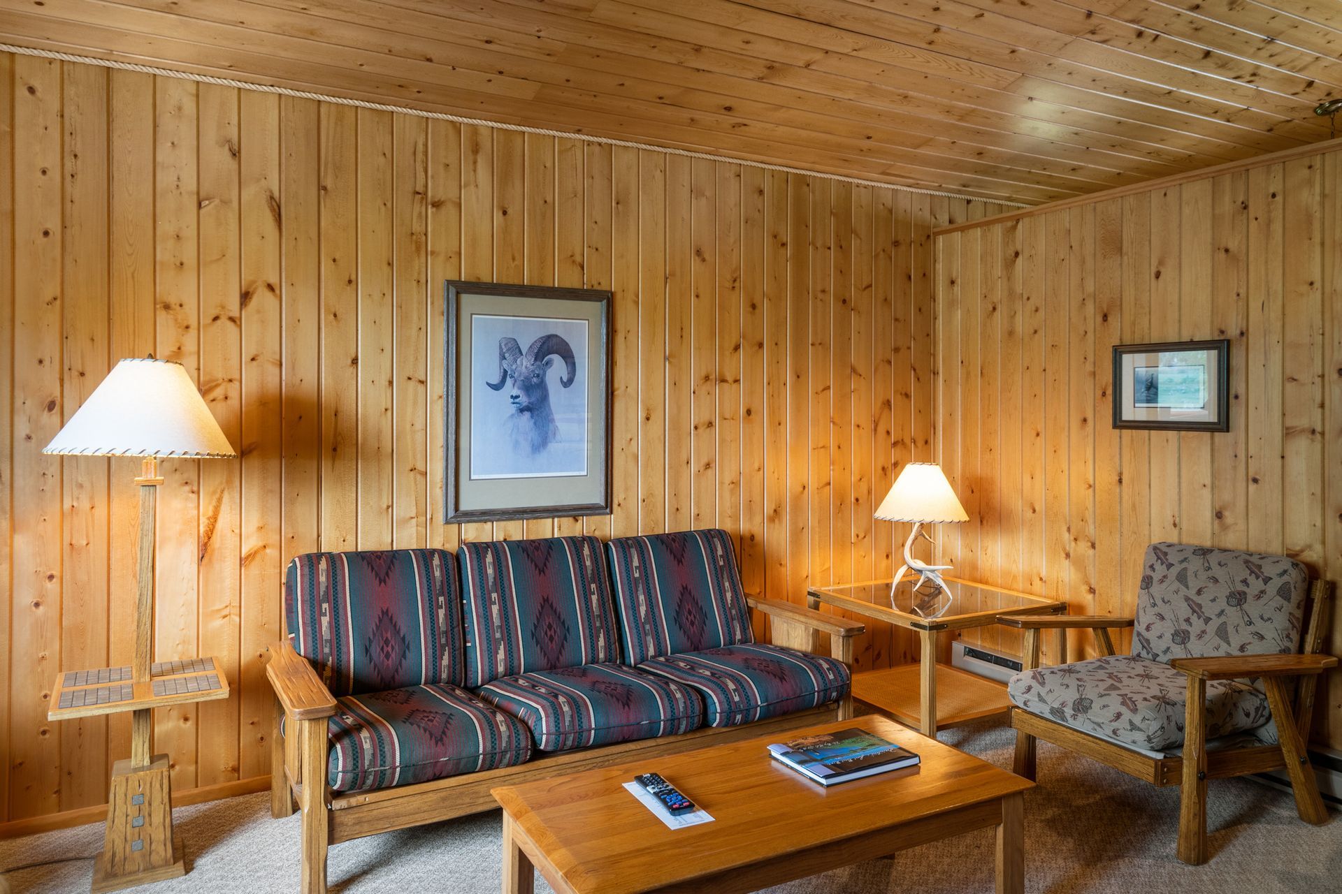 A living room with a couch , chairs , table and lamp.
