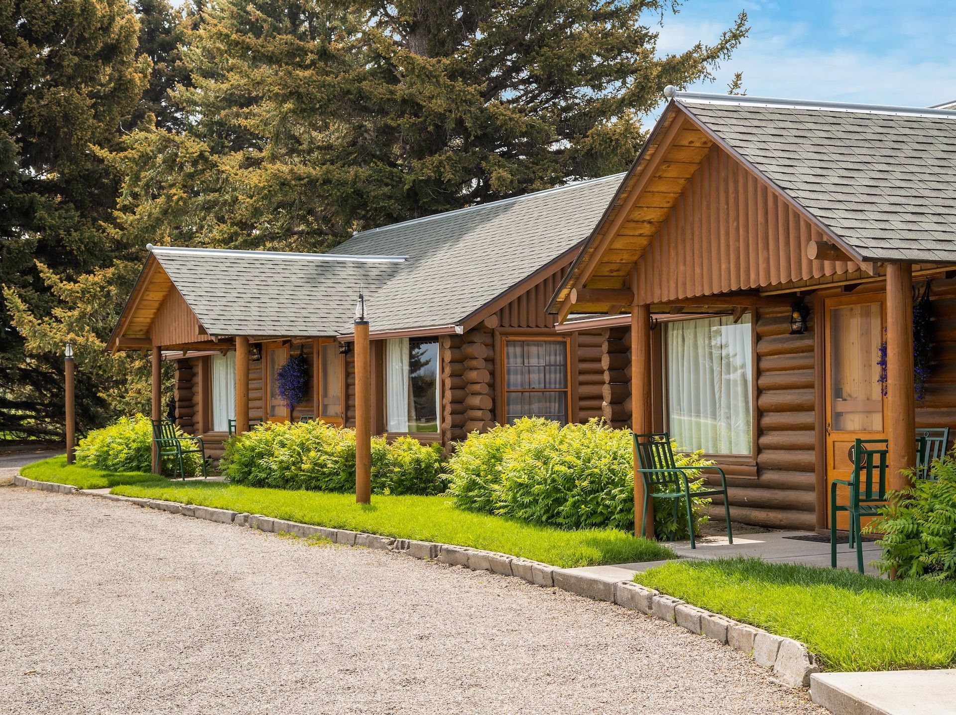 A row of log cabins sitting next to each other on a gravel road.