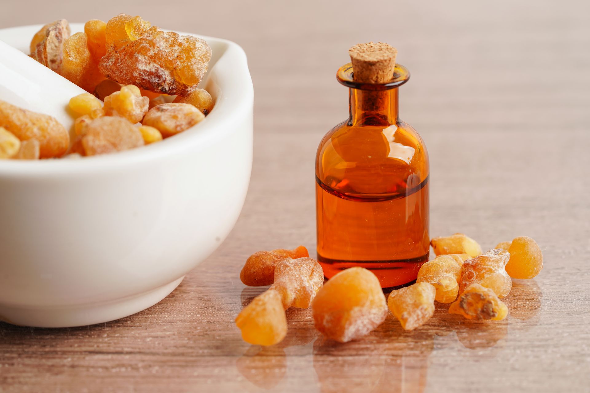 There is a bottle of essential oil next to a bowl of frankincense.