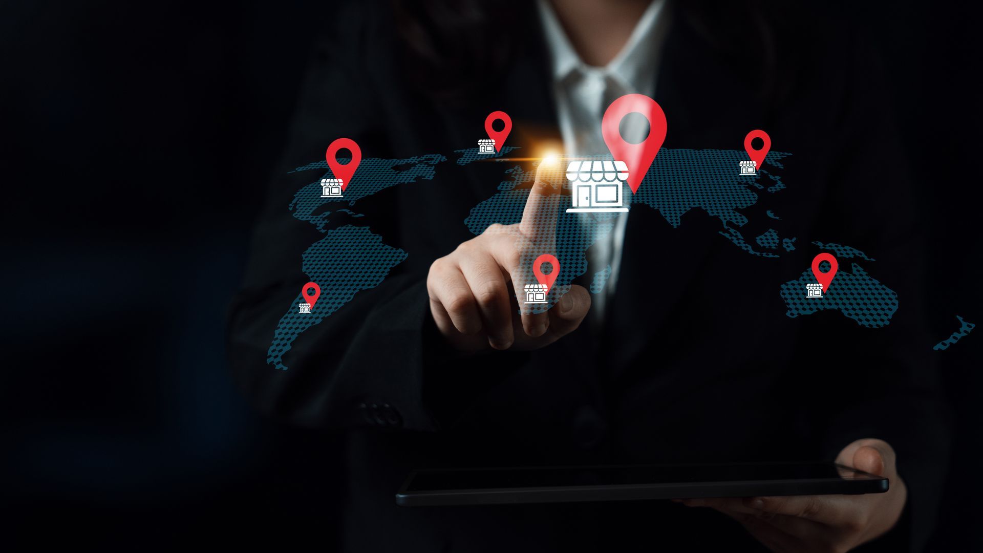 Businessperson touching glowing digital icons on a world map while holding a tablet