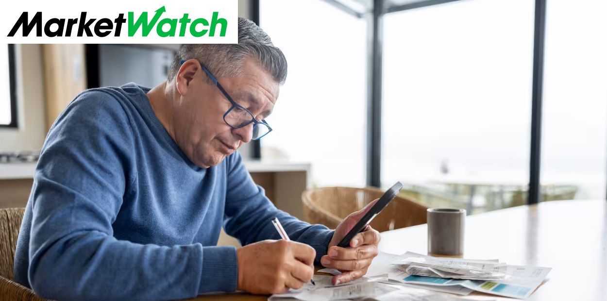 Man reviewing bills and receipts at table while using calculator, reflecting retirement healthcare a