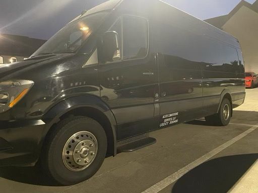 A black van is parked in a parking lot at night.