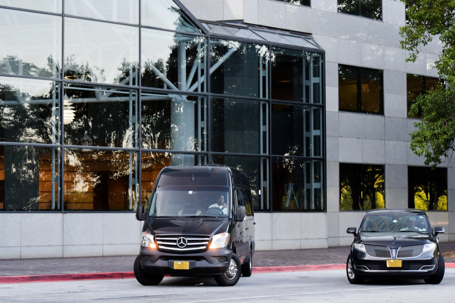 A van and a car are parked in front of a building