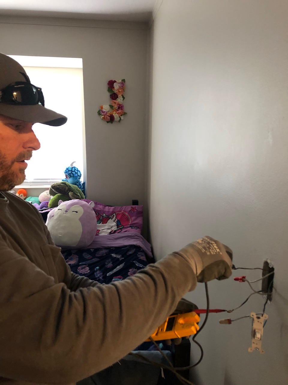 Person holding a model airplane indoors near a bed and window