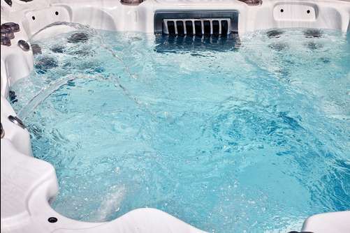 White hot tub with blue bubbling water and built-in headrests