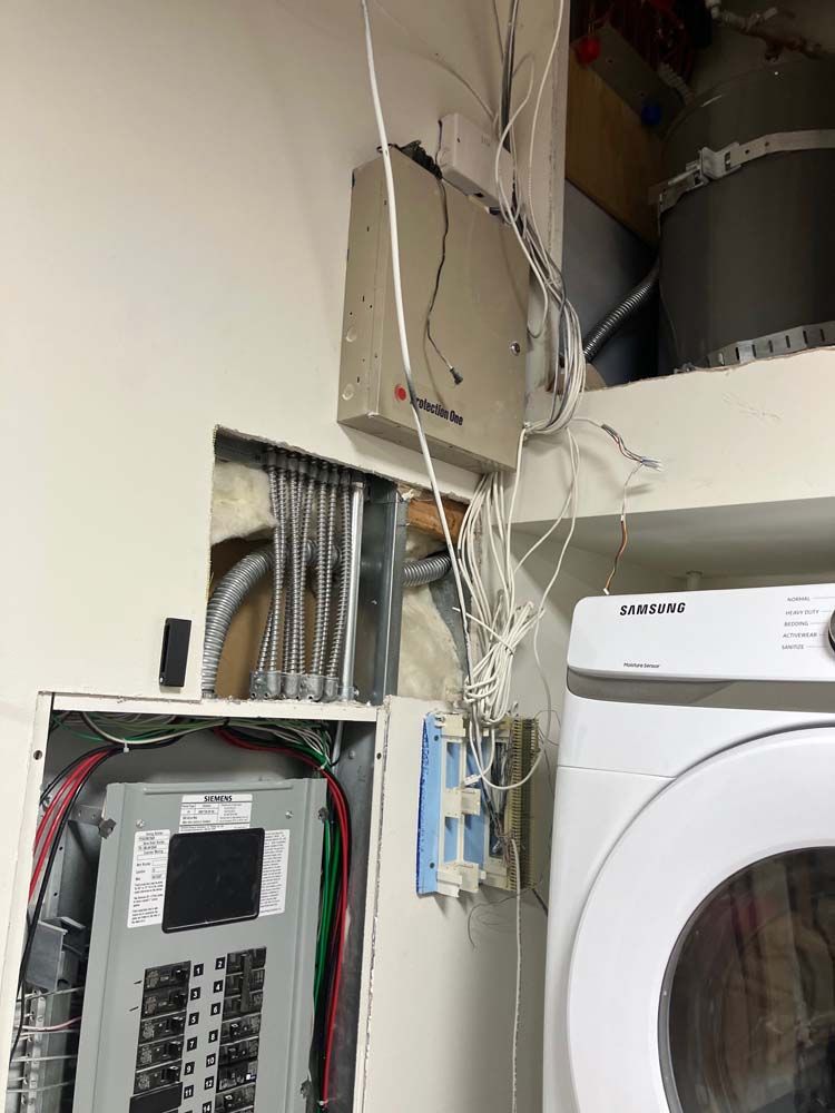 Exposed electrical panel and wiring beside a washer in a utility closet