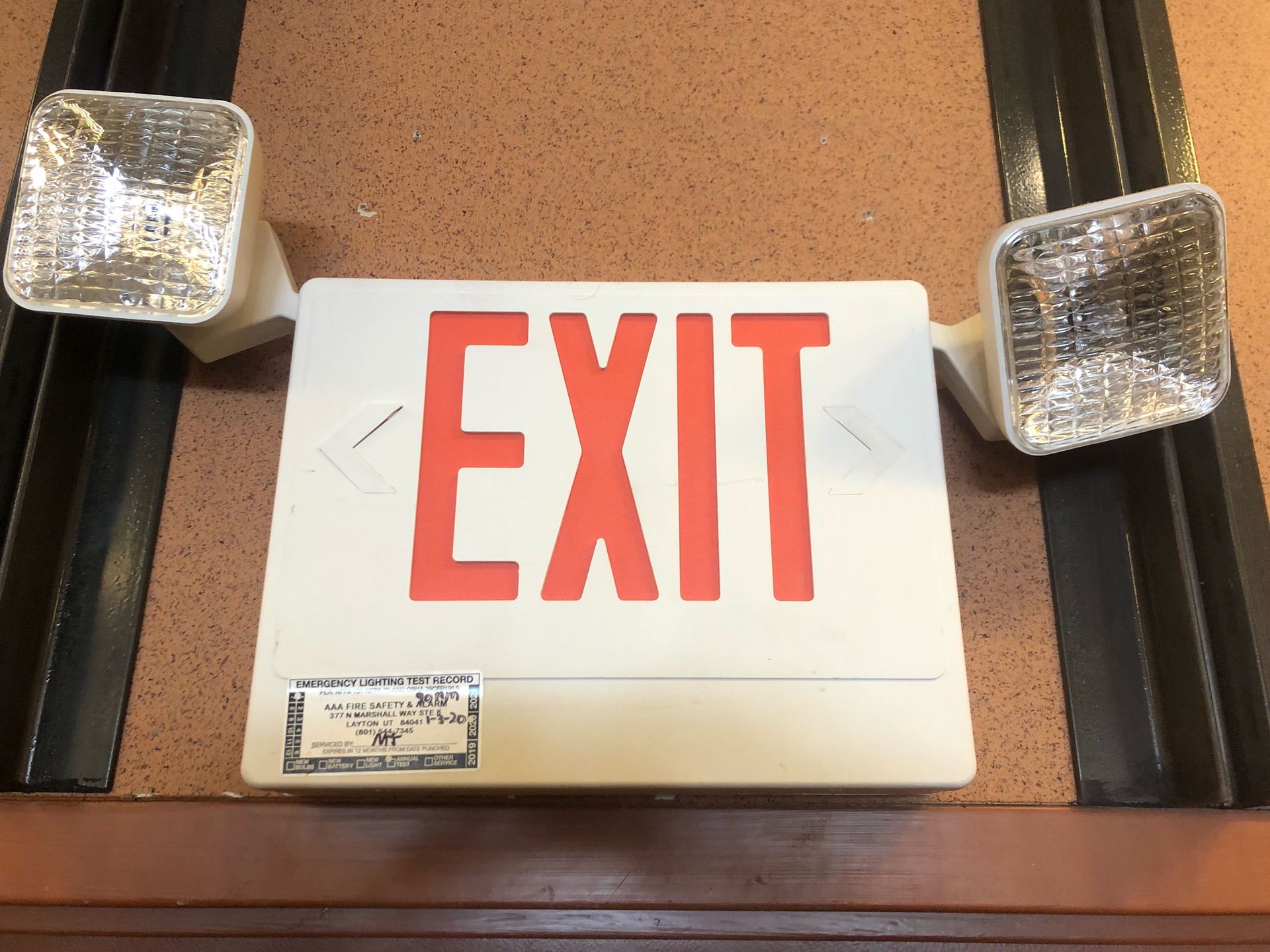 Red EXIT sign above a door, flanked by two emergency lights.