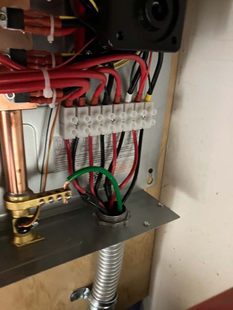 Electrical wiring and terminal block inside a cabinet, with red, black, green, and white cables.