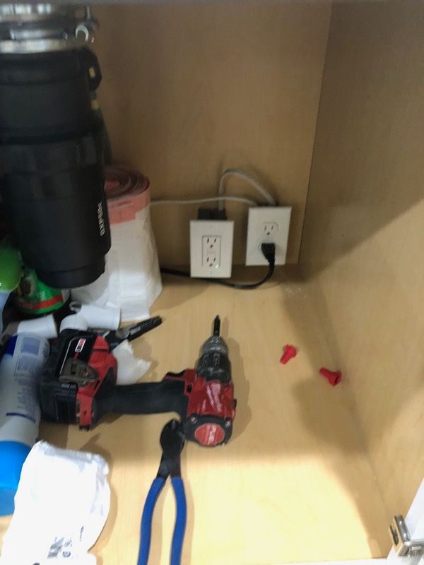 Tools and power cords stored in a cabinet with wall outlets and a flashlight on the shelf