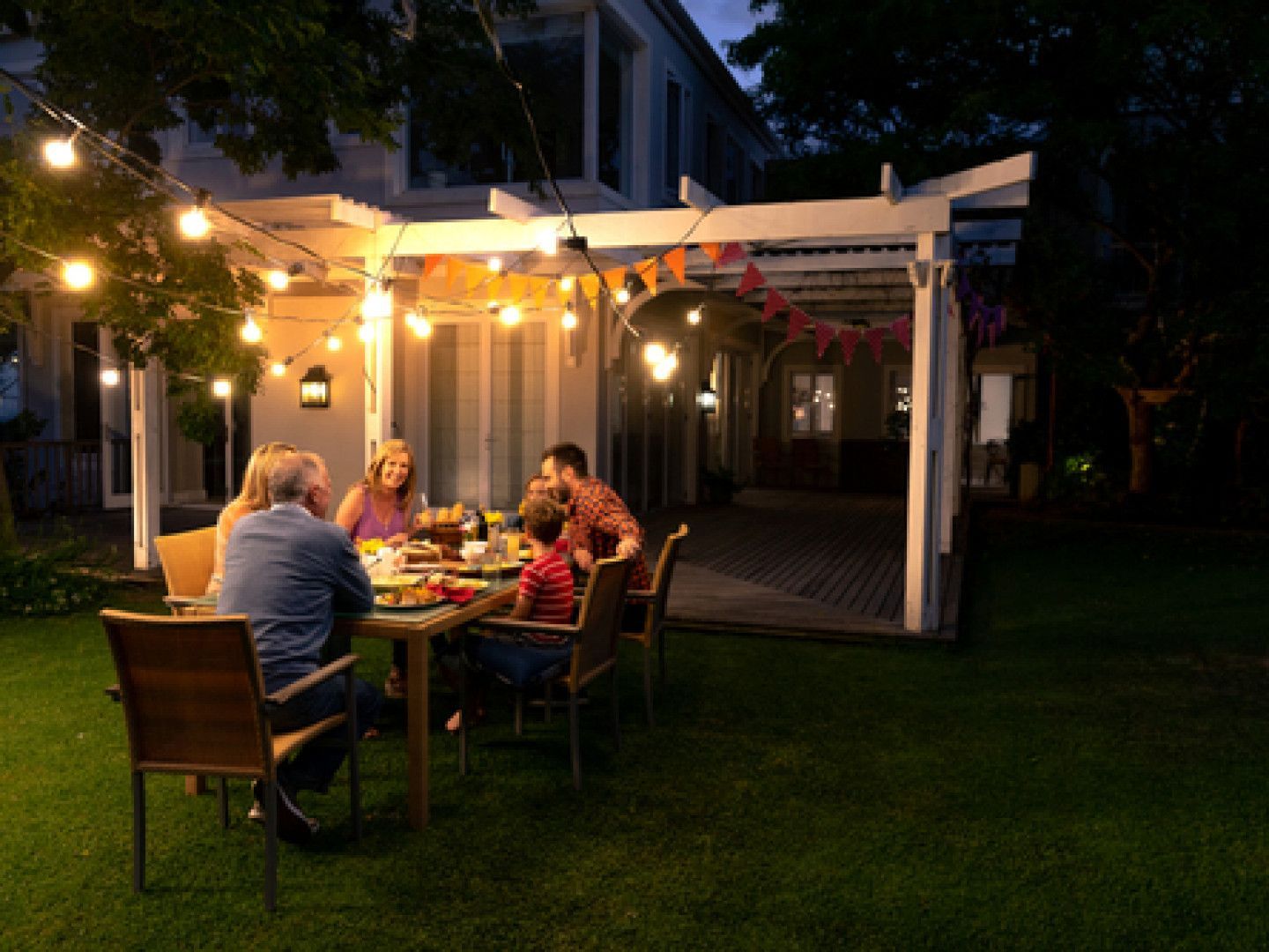 People dining outdoors under string lights on a covered patio at night