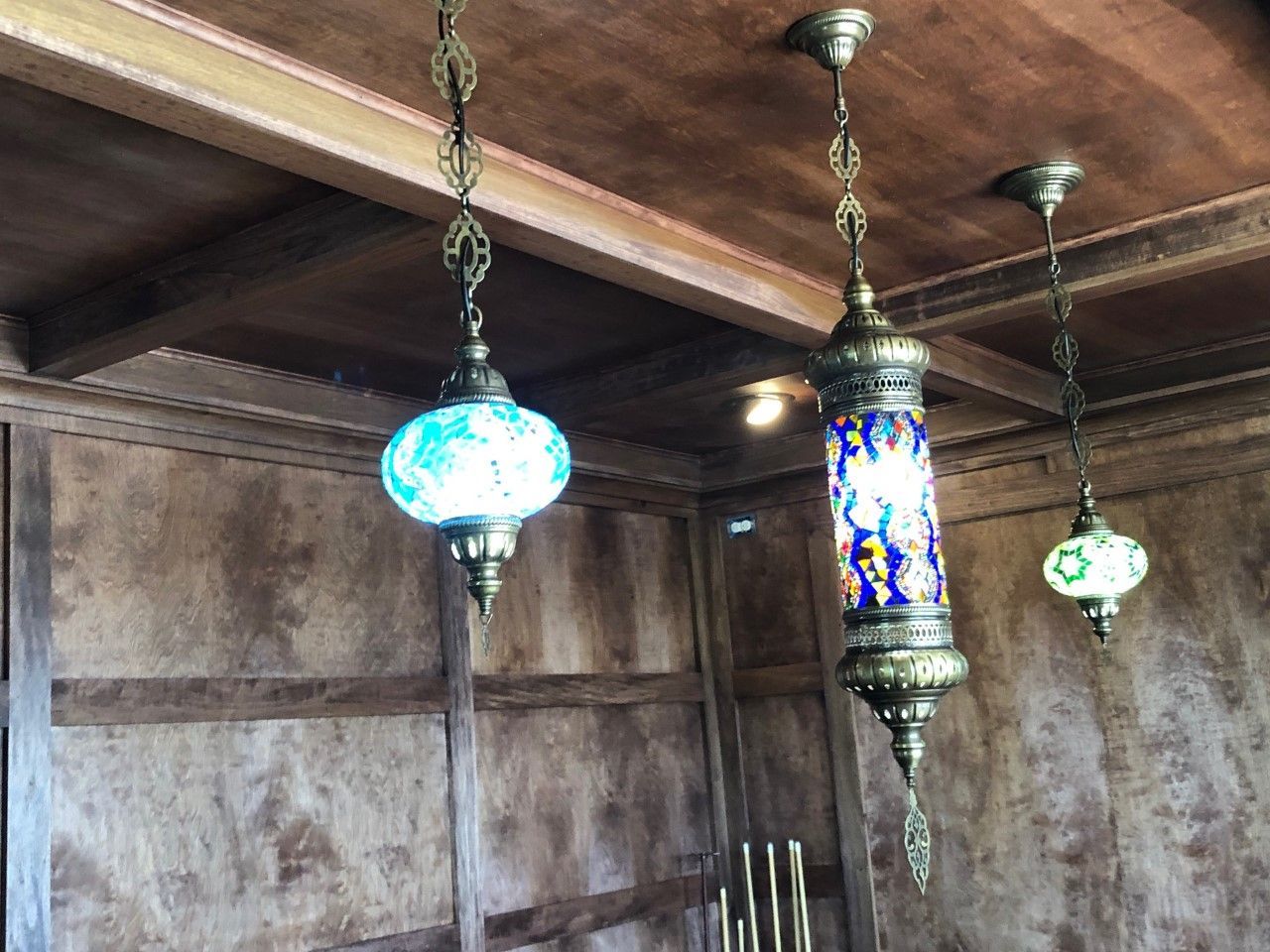 Three hanging stained-glass pendant lamps in a rustic wooden room