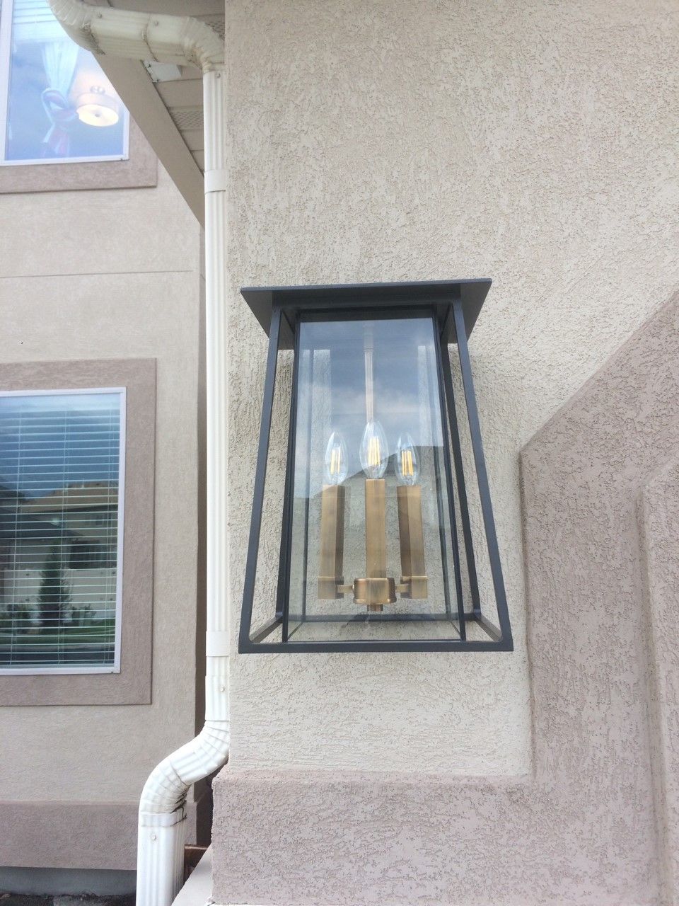 Wall-mounted black metal cage over a small window on a beige stucco exterior wall.